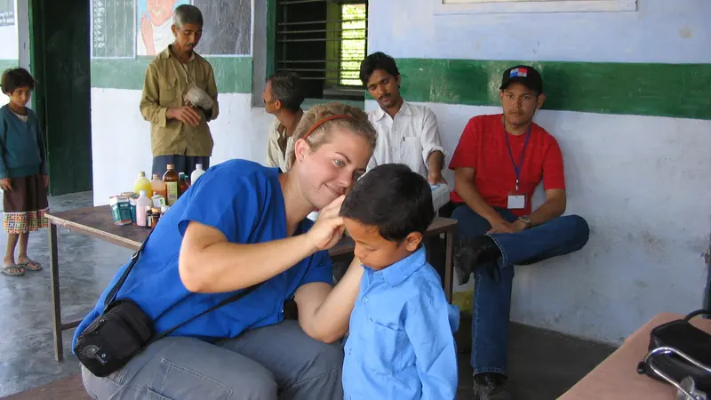 woman checking the ear of a young boy in India