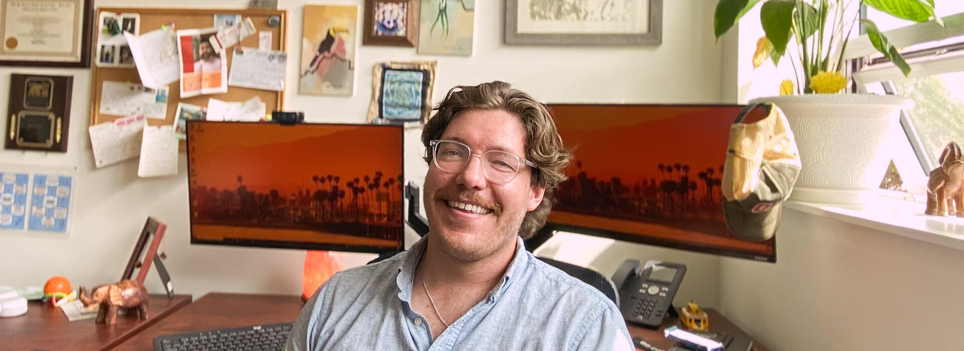 Eric Cole sits at his desk surrounded by international artifacts from his students.